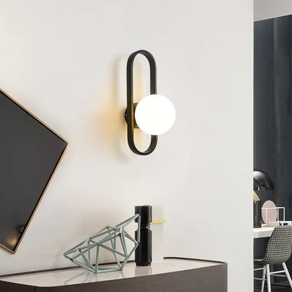 Modern black metal wall sconce lamp with curved frame and frosted glass bulb by decorbites for bedroom and living room