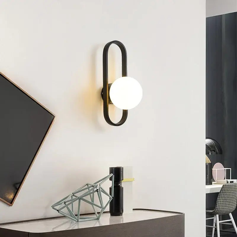 Modern black metal wall sconce lamp with curved frame and frosted glass bulb by decorbites for bedroom and living room