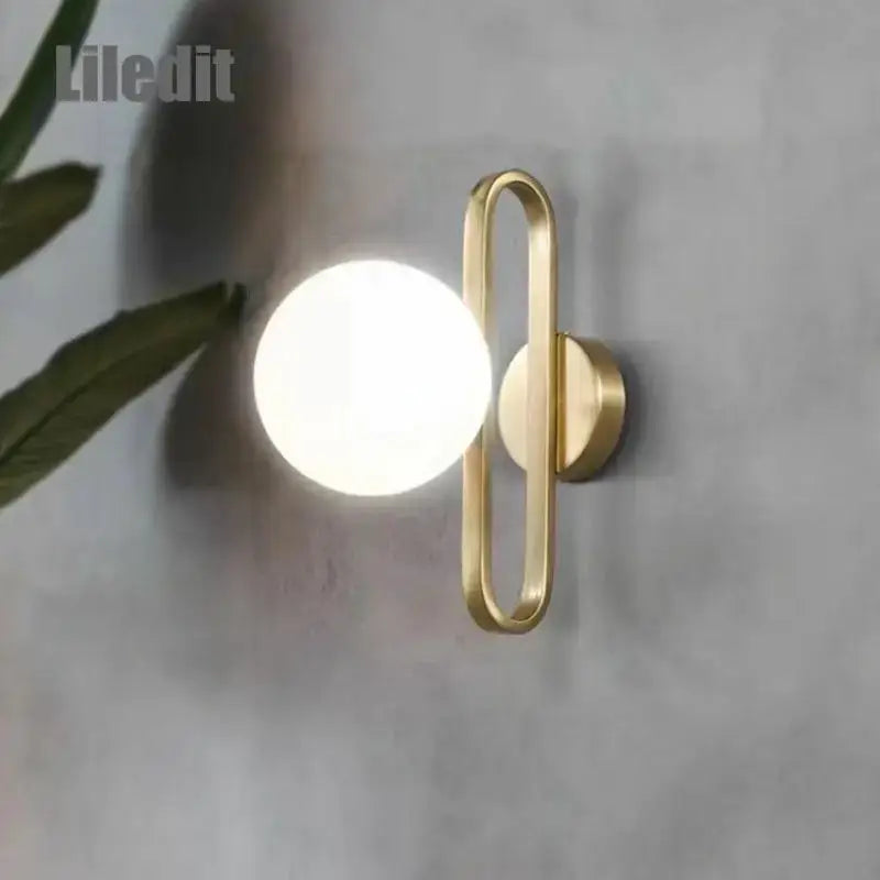 Modern gold-toned DecorBites LED glass wall sconce with oval metal frame and frosted bulb for bathroom or hallway light