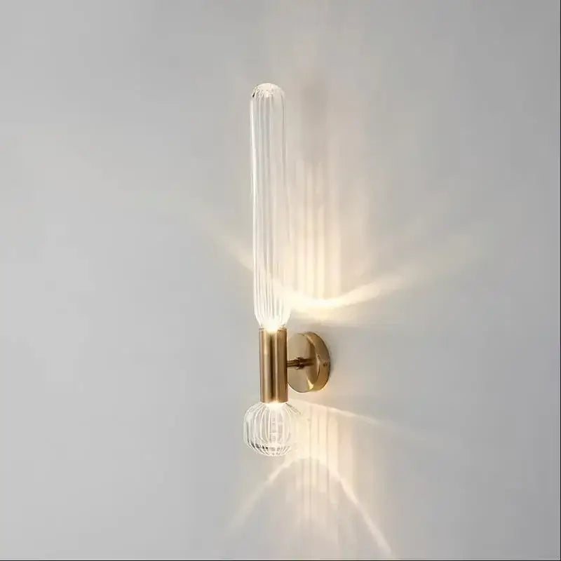 Decorbites™ gold glass wall sconces feature a clear ribbed glass tube and faceted glass globe on a brushed brass fixture