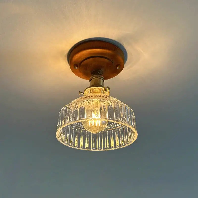 A vintage-style decorbites led glass ceiling light with brass metal base and clear ribbed glass shade for living room