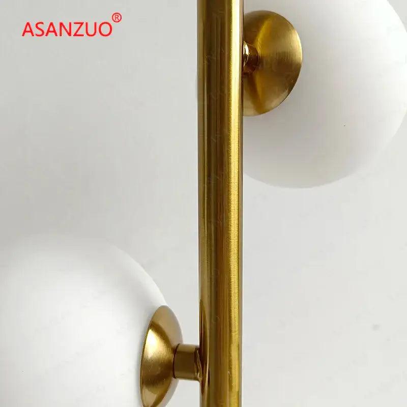 DecorBites table lamp with gold-finished metal pole and milk white glass lampshade featuring white glass spheres