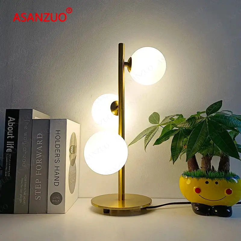 Gold-toned DecorBites™ LED table lamp with three vertical milk white glass lampshades on a slender stem
