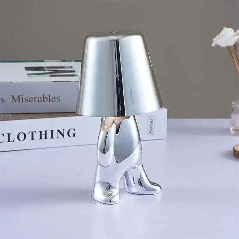 Shiny chrome-plated figurine of a person with high-heeled boots holding an inverted lampshade for DecorBites LED Golden Boy table lamp