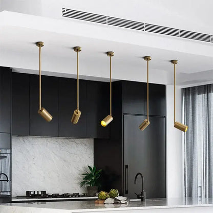 Five elegant brass decorbites led golden ceiling lights with cylindrical heads illuminate a modern kitchen countertop