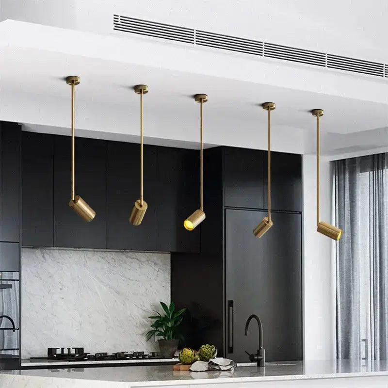 Five elegant brass decorbites led golden ceiling lights with cylindrical heads illuminate a modern kitchen countertop