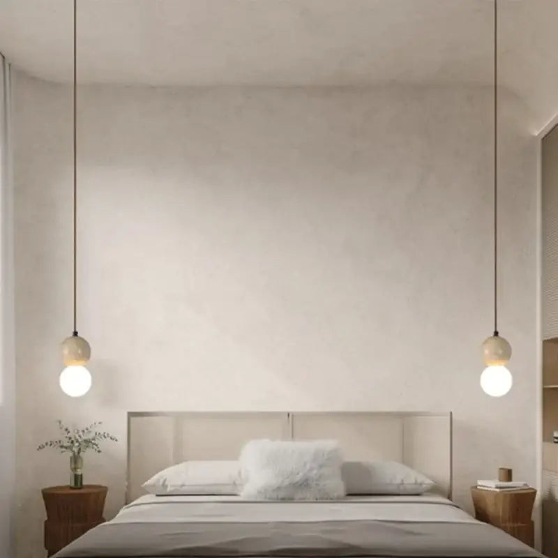 Two minimalist decorbites led gourd pendant lights with white glass shades and yellow travertine hang symmetrically above bed