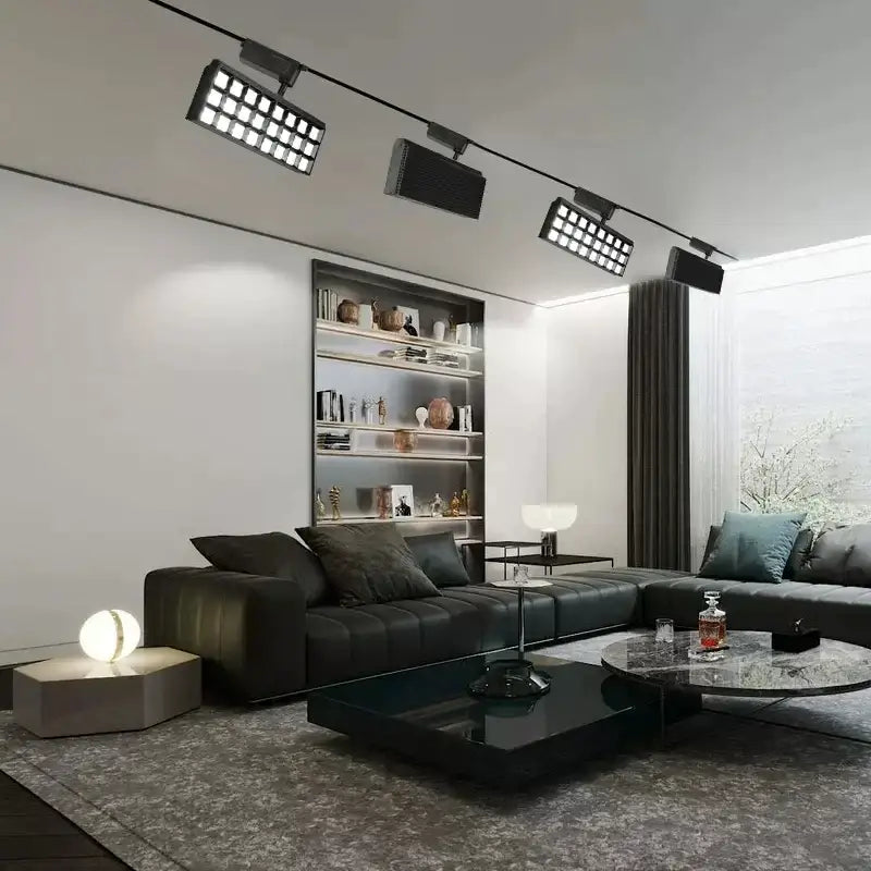 Black leather sectional sofa with tufted cushions and dark gray throw pillows under decorbites led grille track light
