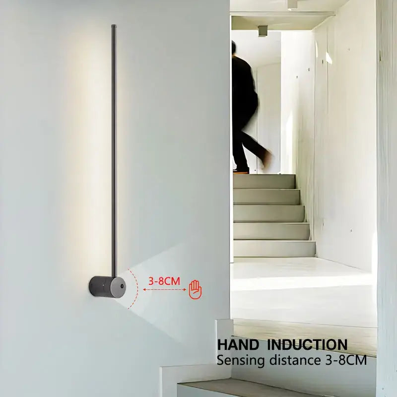 A sleek minimalist decorbites led hand induction wall light with vertical rod and cylindrical base for corridor and bedroom
