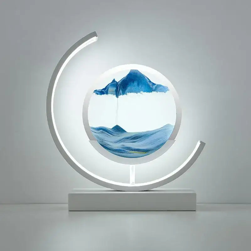 A modern white crescent-shaped decorbites led hourglass lamp with glowing frame and blue silver sand mountainous landscape