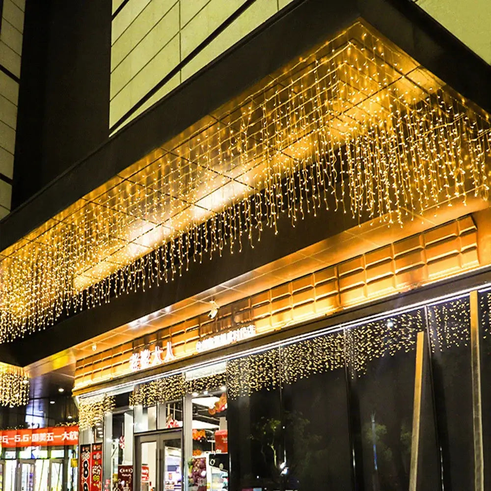 Golden led icicle string lights cascade in a warm curtain pattern at the storefront entrance for outdoor holiday decor
