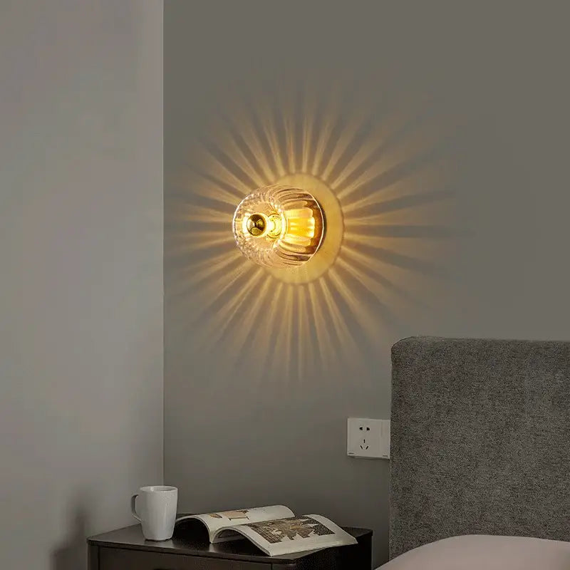 DecorBites LED indoor glass wall sconce with brass accents and faceted globe casting warm sunburst light
