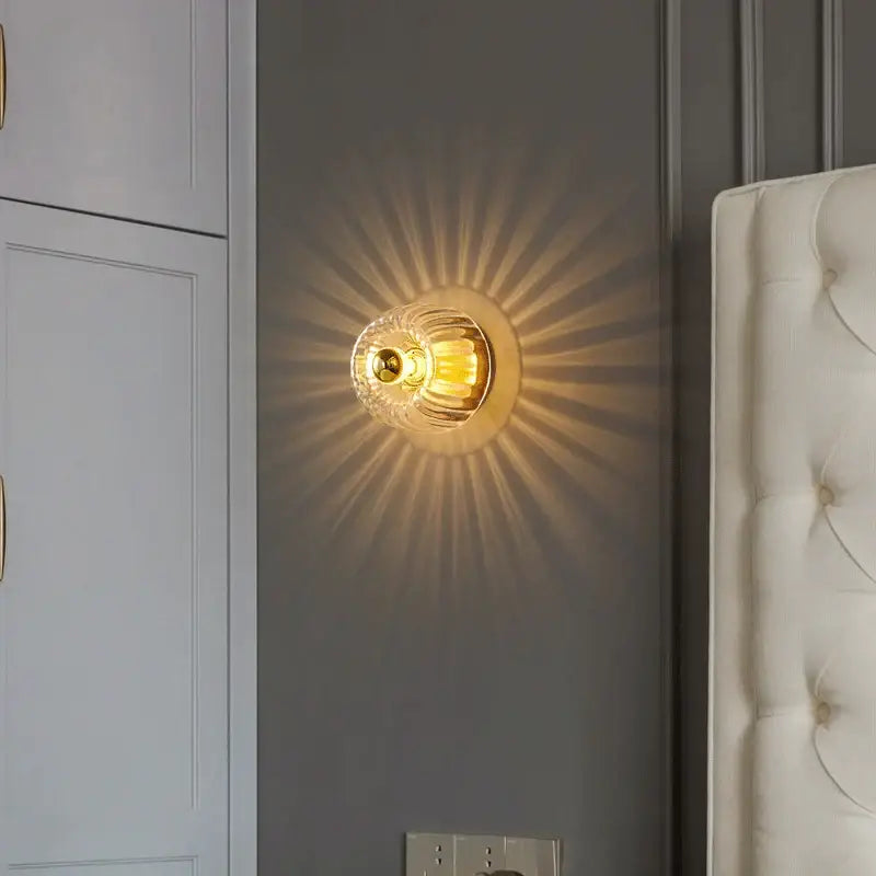 Decorbites led indoor glass wall sconce with golden textured faceted design and brass accents for living room use
