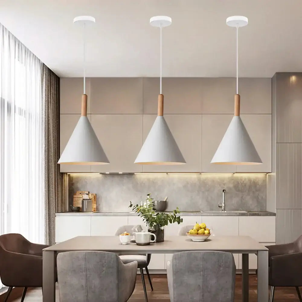 Three white conical shade decorbites led industrial pendant lamps with wooden accents hang above a dining table