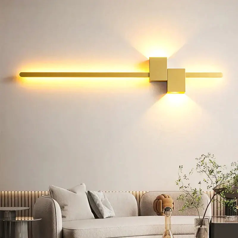 Modern gold-toned decorbites led interior wall lamp with sleek horizontal bar and geometric cube accents emitting warm light