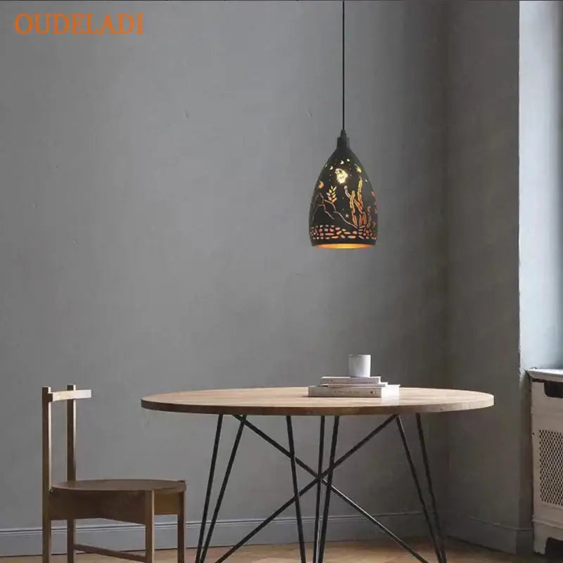 Black pendant light with gold leaf floral and wheat design from decorbites led iron cage, hanging above wooden table