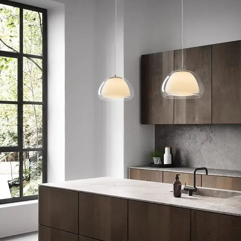 Two modern decorbites led jelly pendant lights with clear glass domes and warm glow hang above kitchen island