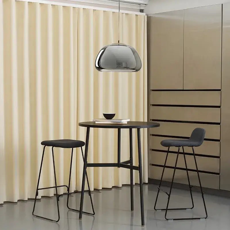 A sleek chrome-finished decorbites led jelly glass pendant light hangs above a black metal table for dining use