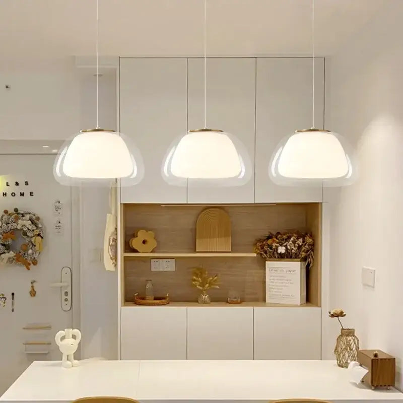 Three modern DecorBites led jelly pendant lights with frosted glass shades and gold fixtures above white countertop