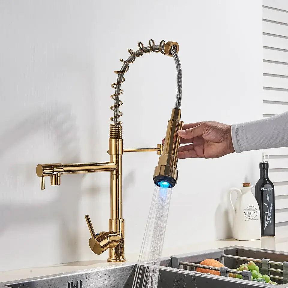 Gold-colored brass decorbites led kitchen faucet with flexible coiled hose and blue illuminated spray nozzle for vessel sink