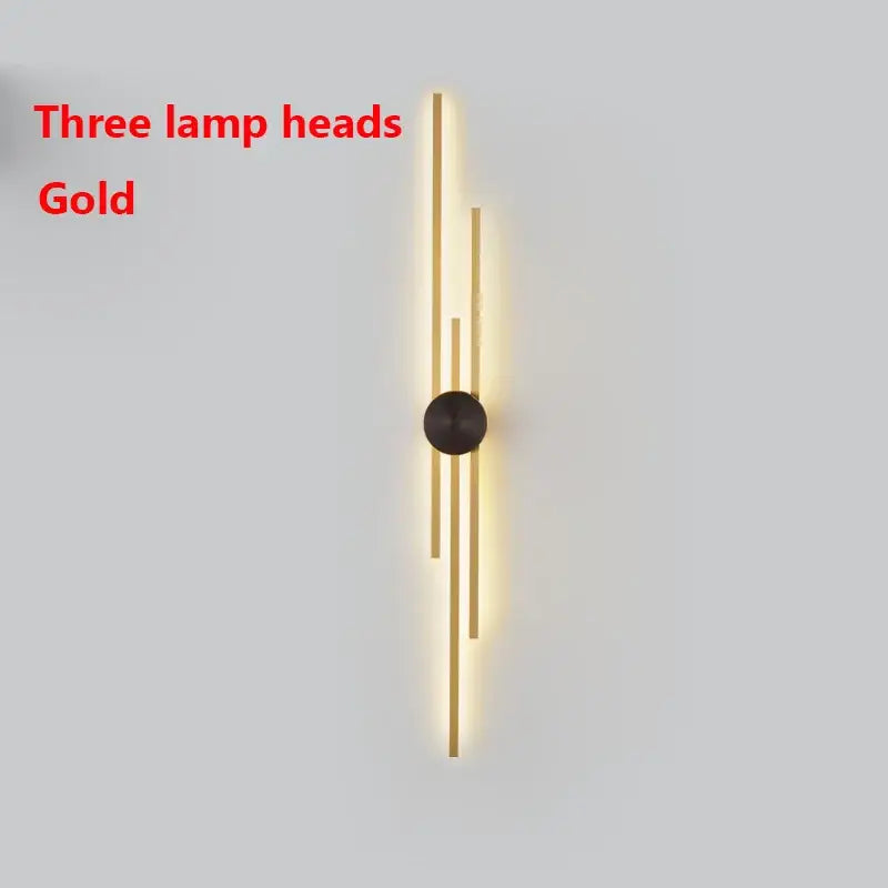 Gold-toned decorbites led long wall lamp with three vertical illuminated heads and dark circular mounting base for living room