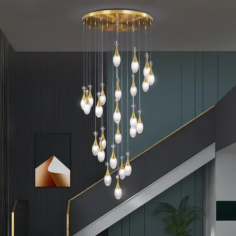 Gold-toned decorbites led luxury chandelier with teardrop glass pendants from circular brass fixture for modern living spaces