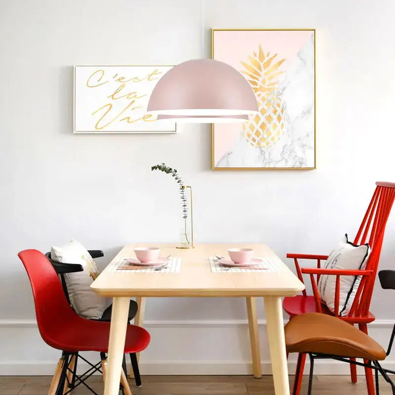 A modern dome-shaped matte pink pendant light hangs above the dining table decorbites led macaron pendant