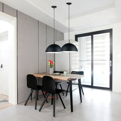Modern black decorbites led macaron pendant lights with sleek dome-shaped shades hang above a dining table