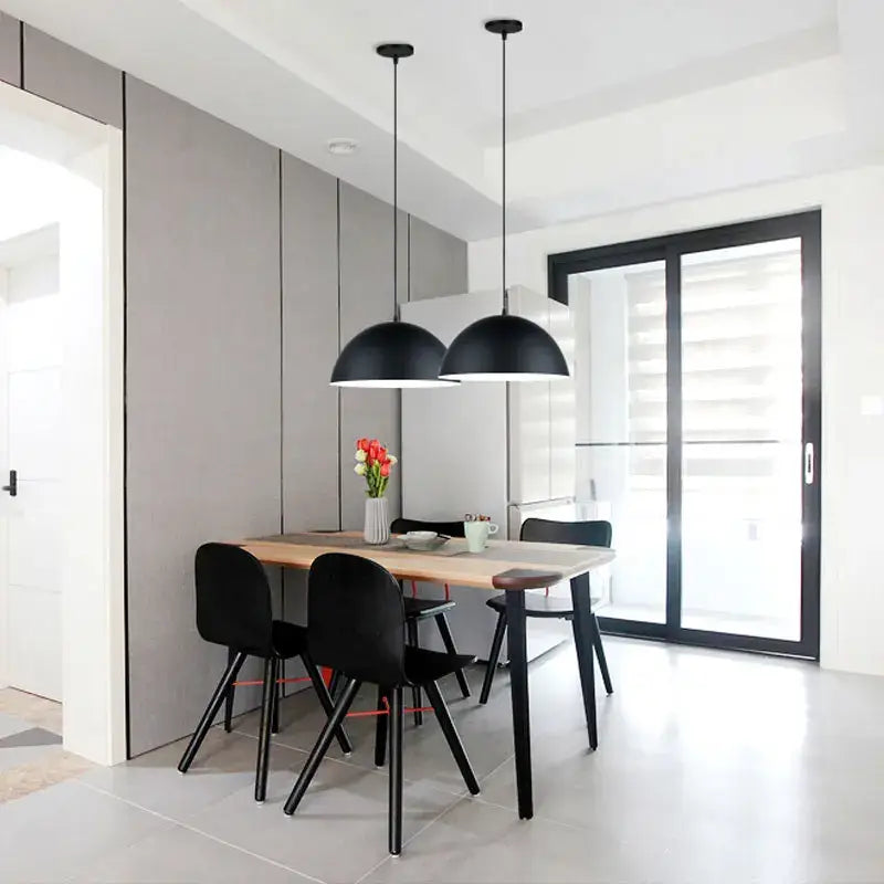 Modern black decorbites led macaron pendant lights with sleek dome-shaped shades hang above a dining table