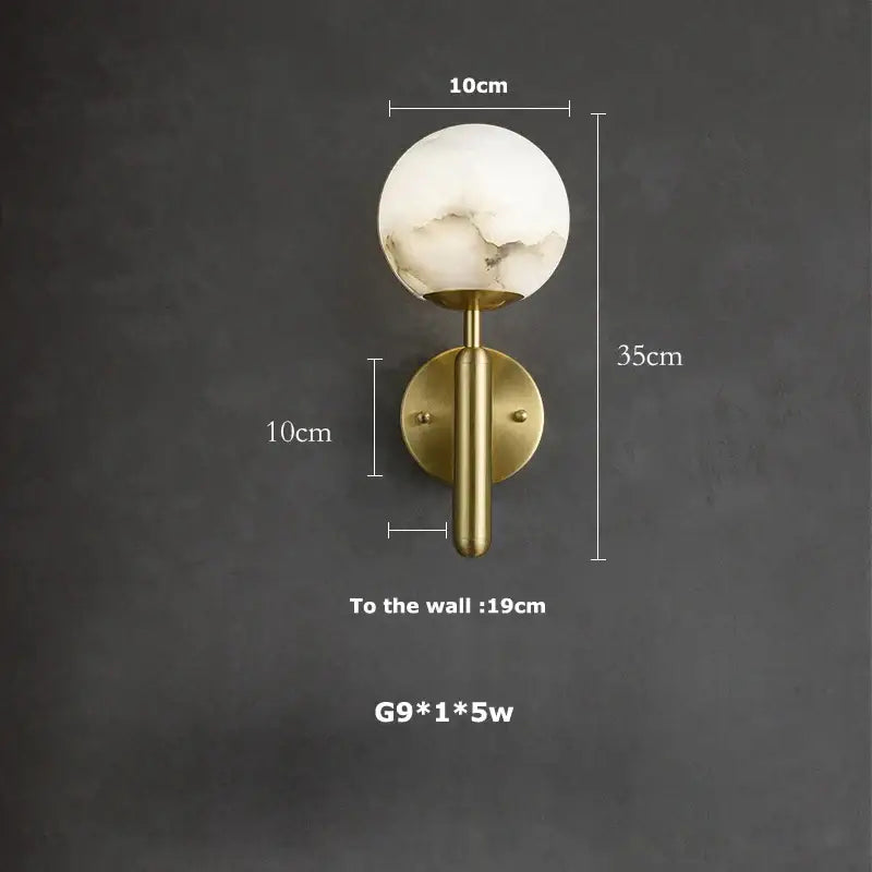 A modern decorbites led marble wall sconce with a white marble globe and brass stem for dining room lighting