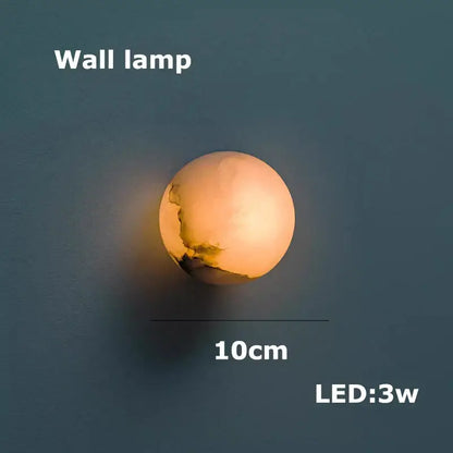 A warm glowing spherical decorbites led marble wall lamp with textured surface for dining room chandelier use
