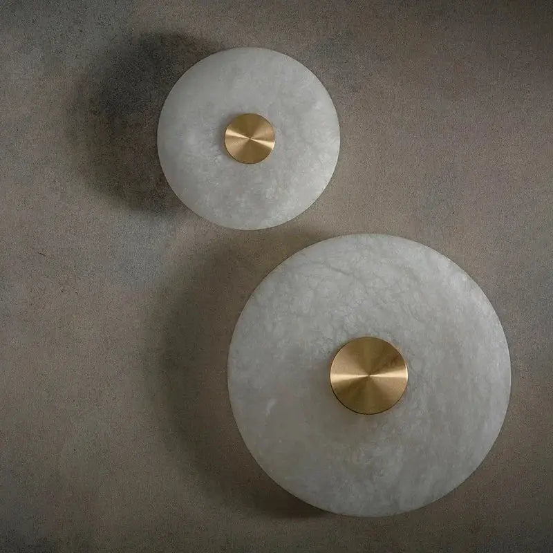 Two circular white marble decorbites led marble brass wall sconces with polished centers for parlor and aisle lighting