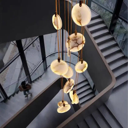 A modern decorbites led marble pendant lamp with circular white and beige agate discs and gold-toned chains for living room