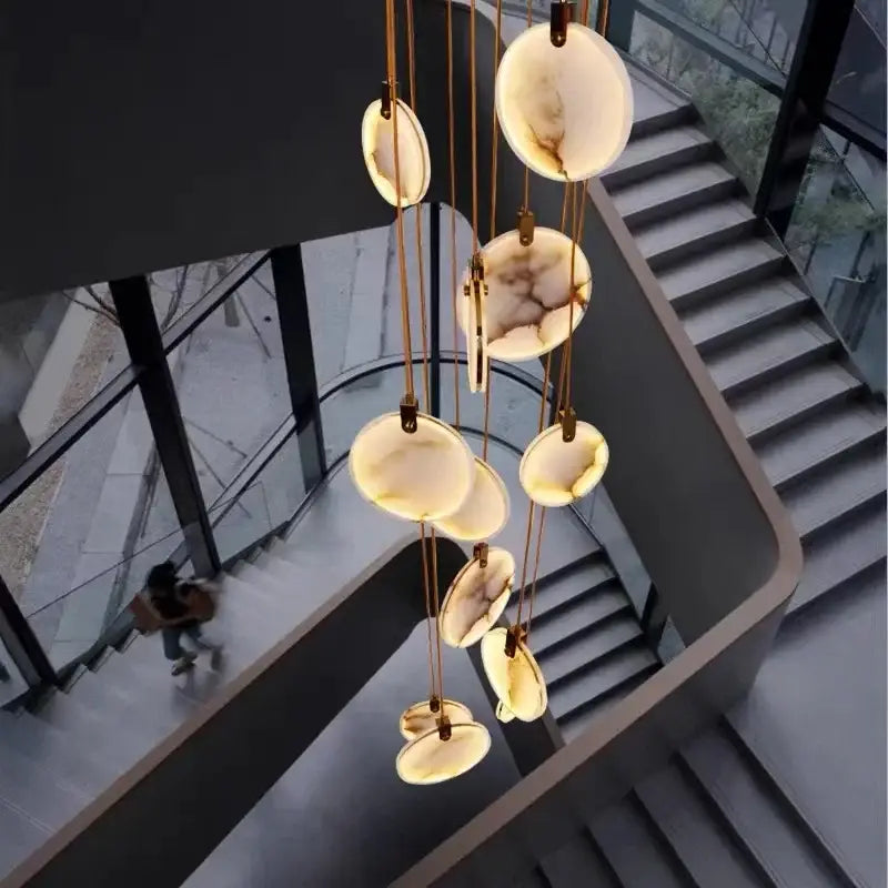 A modern decorbites led marble pendant lamp with circular white and beige agate discs and gold-toned chains for living room