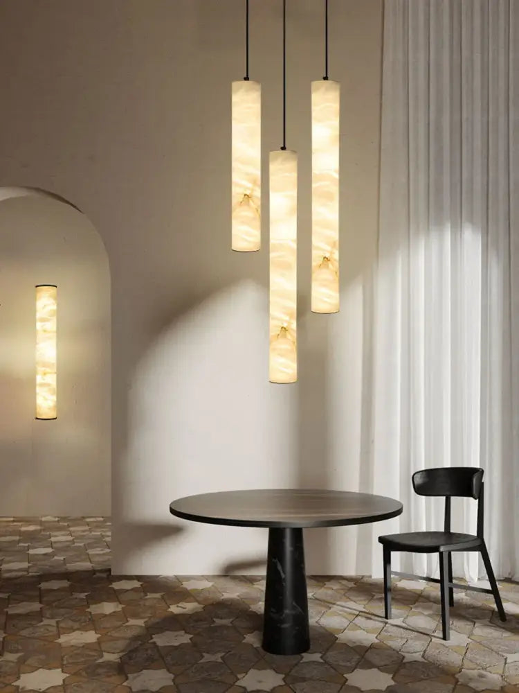 Three cylindrical led marble hanging lamps in white alabaster translucent material hanging from the ceiling