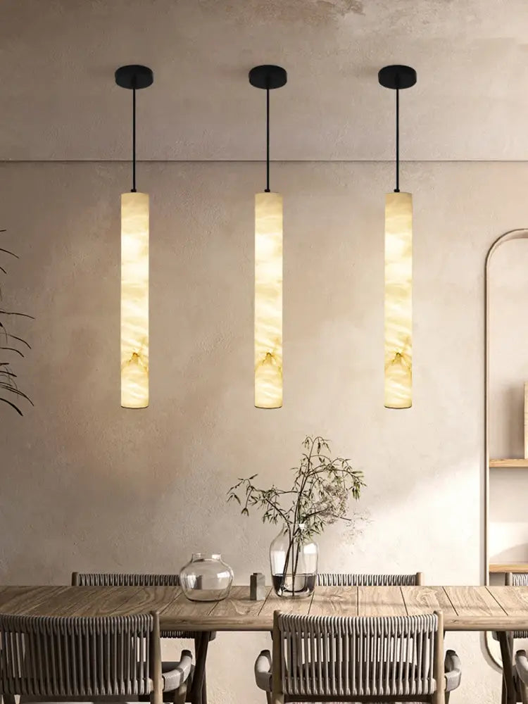 Three elegant led marble hanging lamps with warm beige and cream white alabaster shades hang from black fixtures