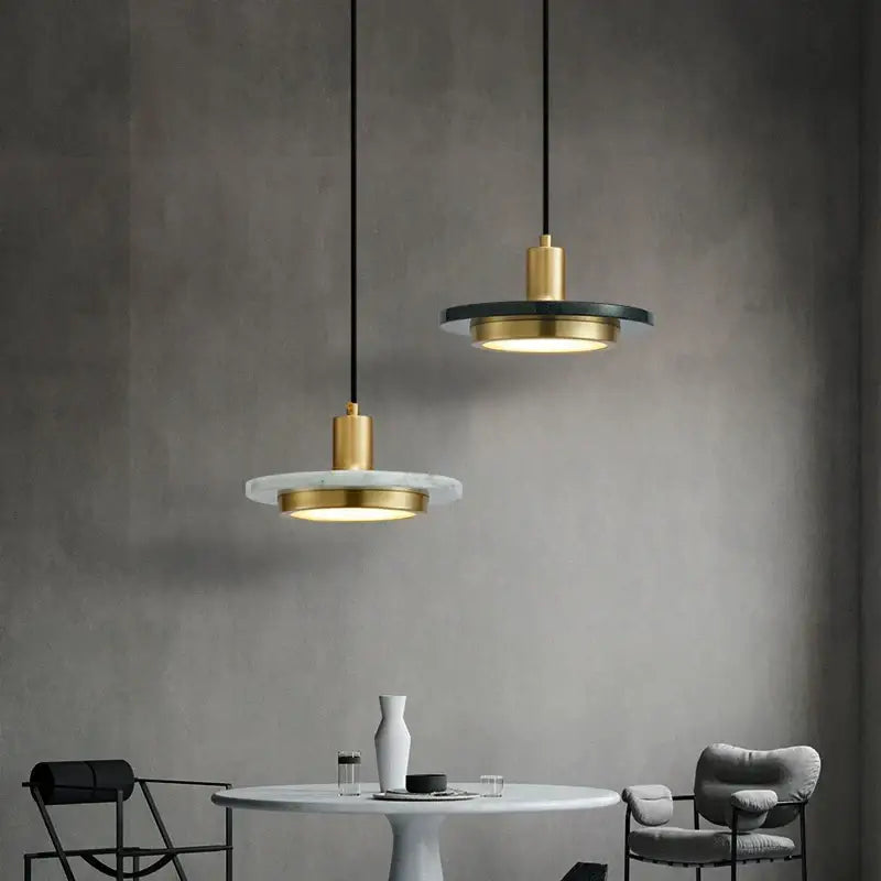 Two modern DecorBites LED marble pendant lamps with gold metal fixtures and white and black circular marble plates