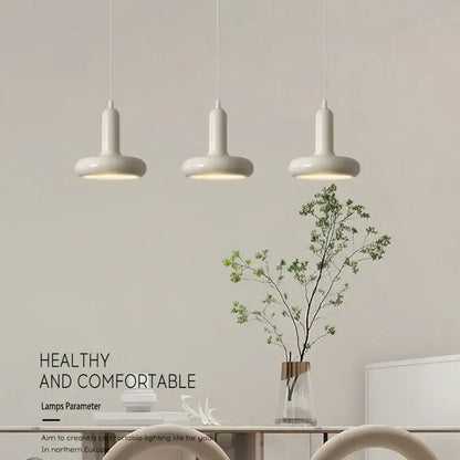 Three white decorbites led minimalist nordic pendant lamps with cylindrical shades in a modern dining space