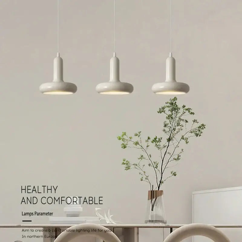 Three white decorbites led minimalist nordic pendant lamps with cylindrical shades in a modern dining space
