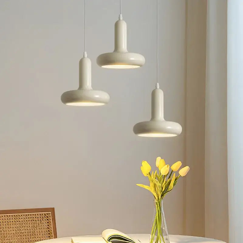 Three off-white ceramic decorbites led minimalist pendant lights with a nordic design hanging in a living room setting