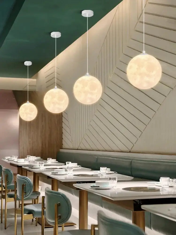 Warm glowing spherical pendant lights with a moon surface design in decorbites led moon planet ceiling chandelier