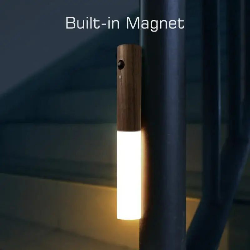 Wooden-handled DecorBites LED motion sensor night light with warm white illuminated cylinder and USB recharge features