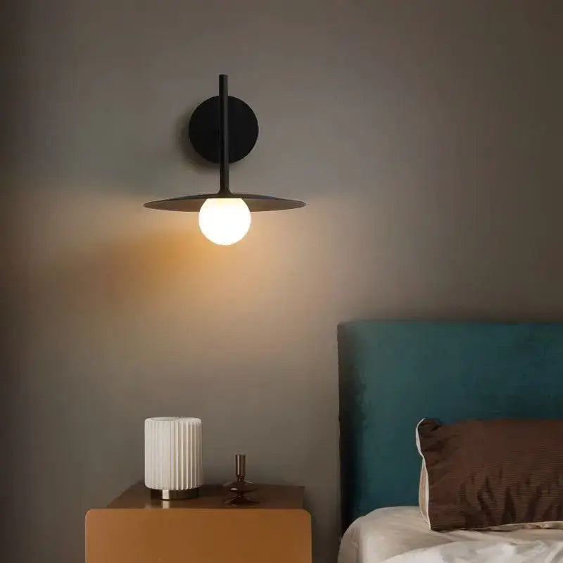Black minimalist wall lamp with circular base and flat disc shade featuring a warm globe bulb decorbites led movable arm