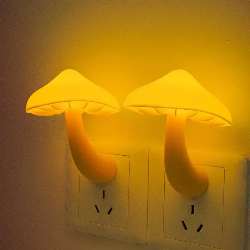 Two glowing yellow decorbites led mushroom night lights plugged into wall sockets with light controlled sensor for bedroom use