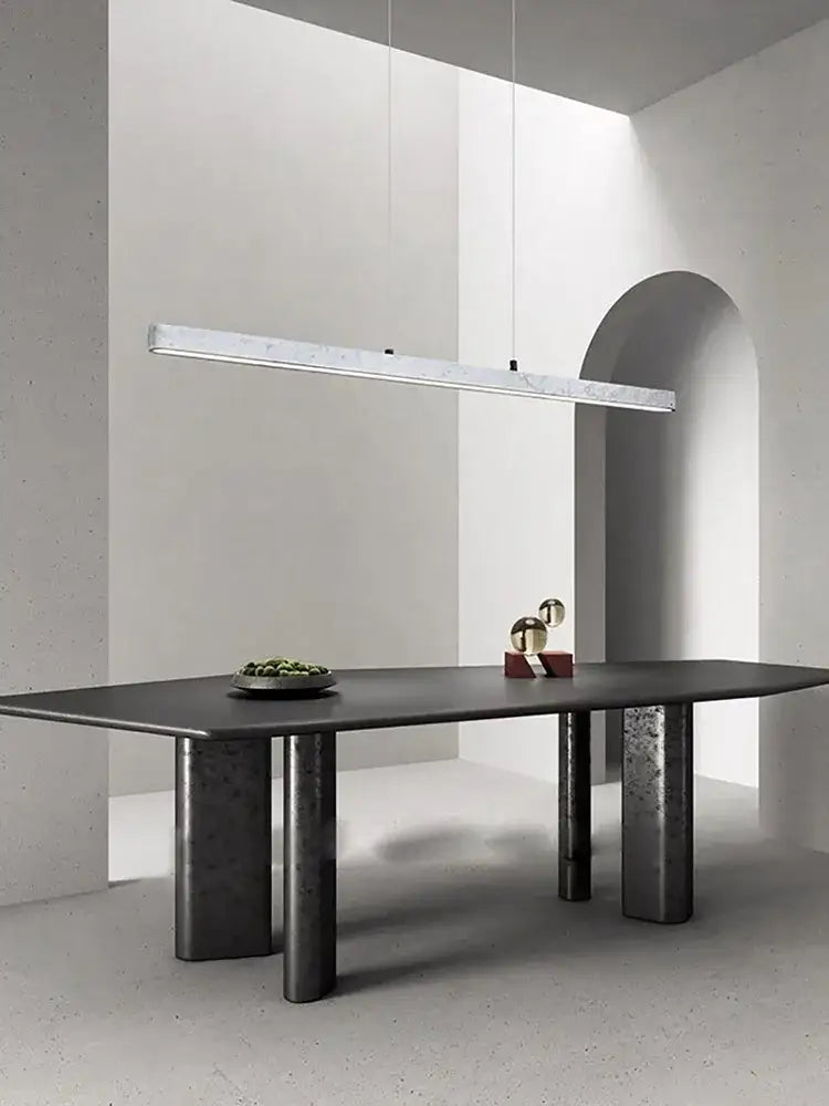 Modern black matte dining table with cylindrical metal legs beneath decorbites led natural marble hanging chandelier