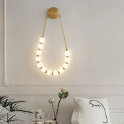 Gold-toned DecorBites LED Necklace wall lights with circular glowing bulbs in black metal and white acrylic sconce design