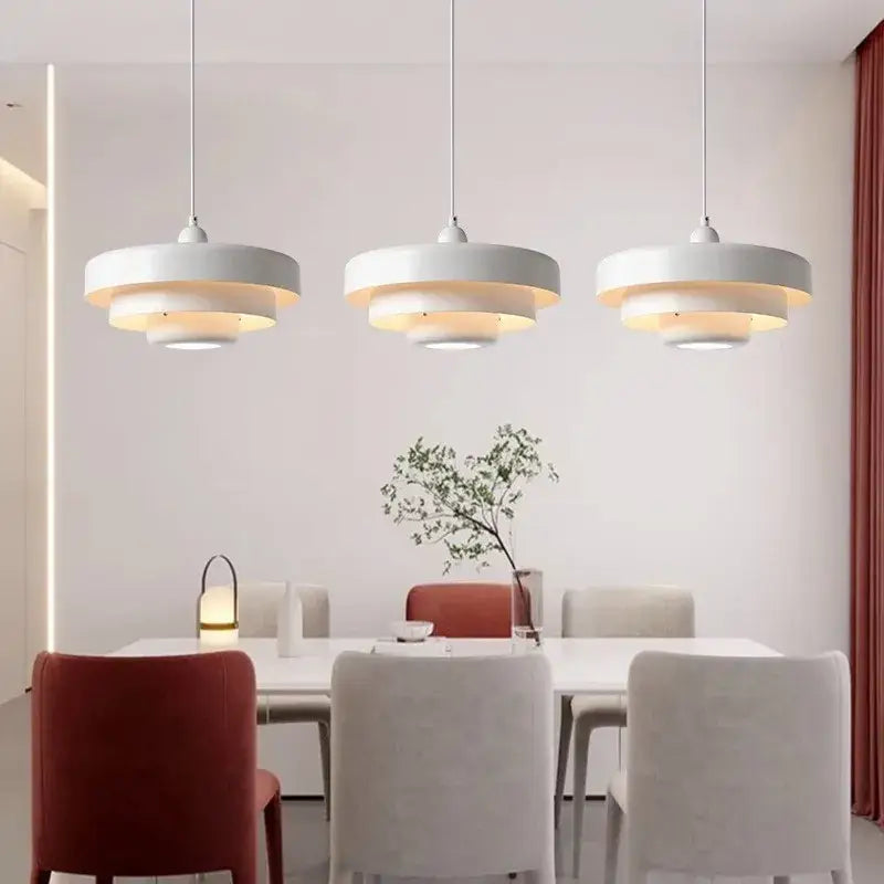 Three modern white decorbites led nordic pendant lights with layered circular shades hang above a dining table