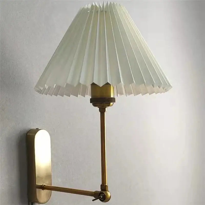 A brass decorbites led origami wall lamp with pleated off-white shade and adjustable arm for bedroom and living room use