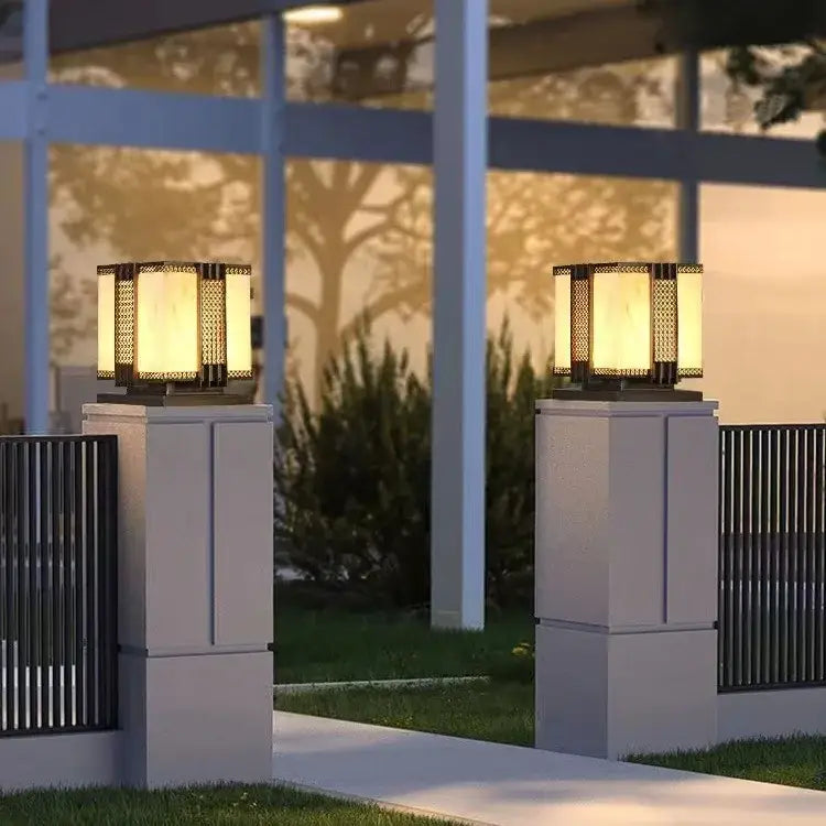 Two elegant DecorBites LED outdoor marble street lamps with warm yellow light and golden mesh panels on white pillars