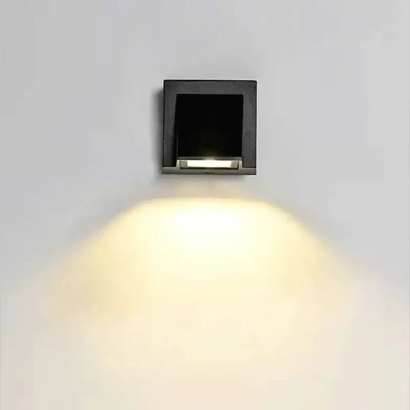 Black square DecorBites LED outdoor wall light with sleek modern design and warm yellow illumination for porch use